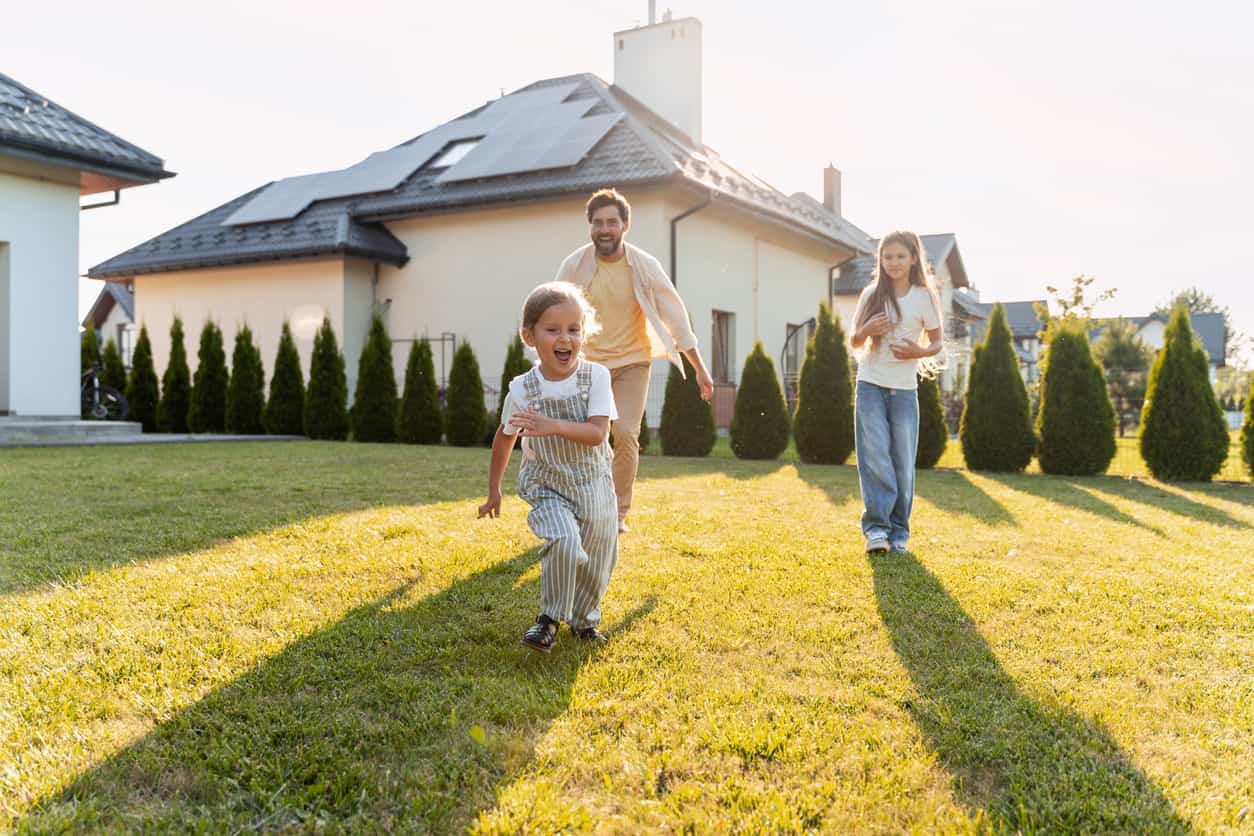 Familie spielt im Garten vor modernem Haus — Familiengründung