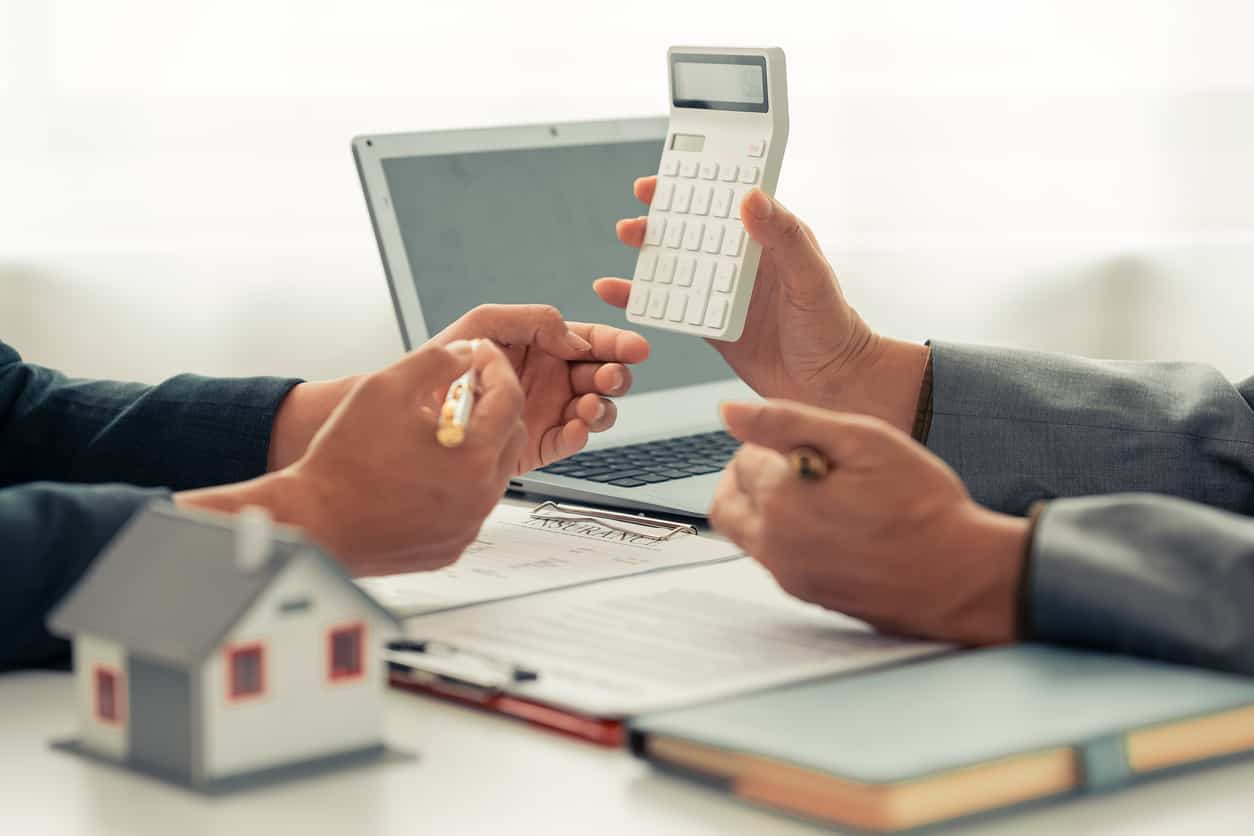 Beratungsgespräch mit Taschenrechner und Modellhaus — Immobilienfinanzierung